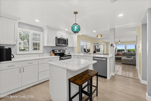 kitchen featuring kitchen peninsula, light wood-type flooring, stainless steel appliances, and a healthy amount of sunlight