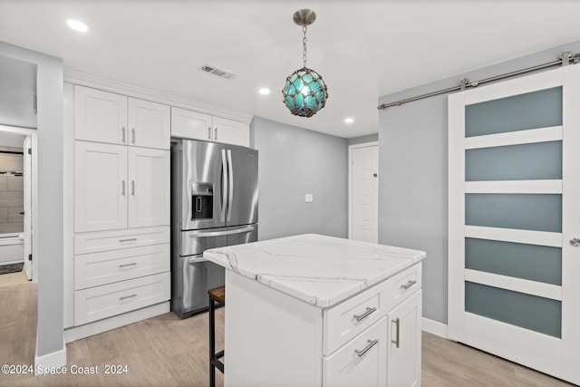 kitchen featuring stainless steel fridge with ice dispenser, white cabinets, a barn door, light hardwood / wood-style floors, and a kitchen island