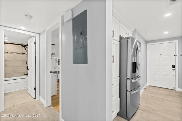 clothes washing area featuring electric panel and light hardwood / wood-style floors