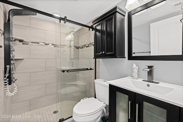 bathroom featuring vanity, a shower with door, and toilet