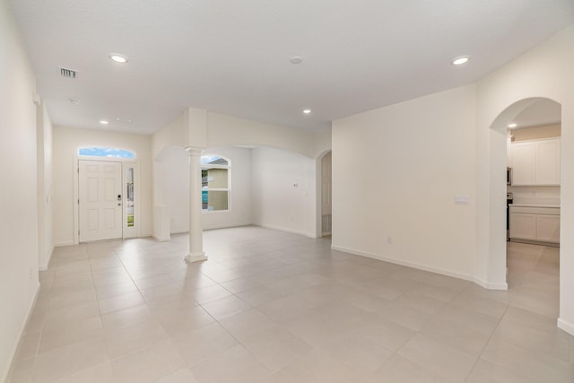 empty room featuring decorative columns and light tile patterned flooring