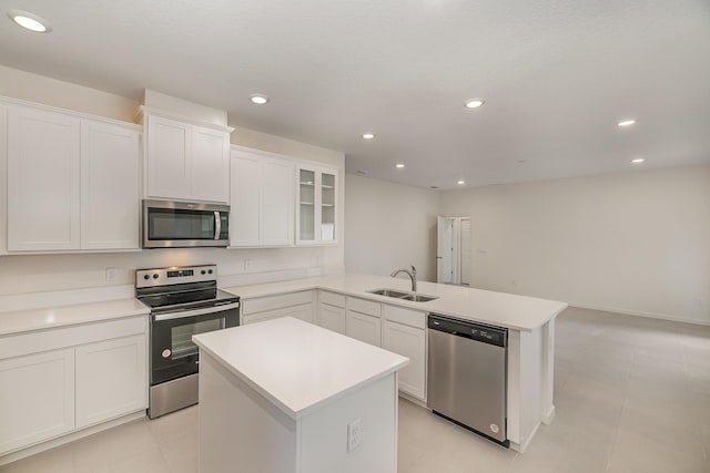 kitchen featuring sink, white cabinetry, stainless steel appliances, a kitchen island, and kitchen peninsula