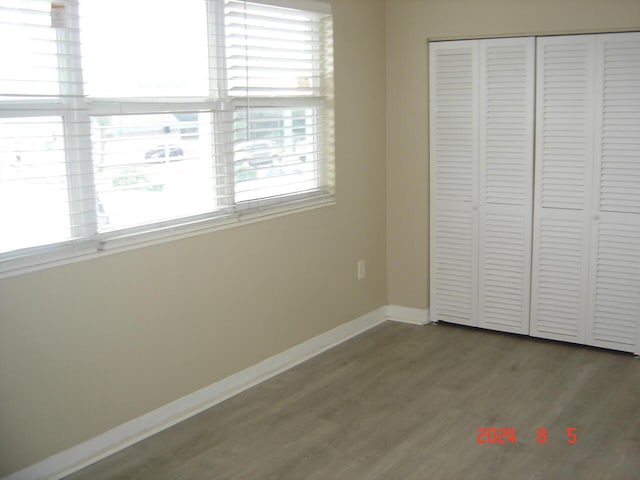 unfurnished bedroom featuring a closet, baseboards, and wood finished floors