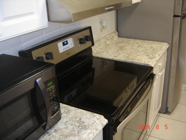 kitchen featuring light stone countertops, light tile patterned floors, and stainless steel appliances