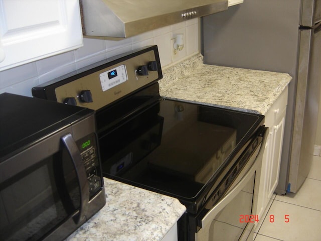 kitchen with appliances with stainless steel finishes, light stone counters, and light tile patterned floors