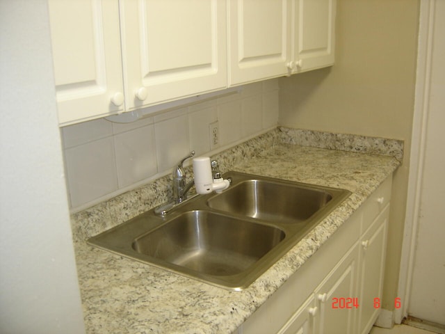 kitchen with sink, white cabinets, decorative backsplash, and light stone countertops