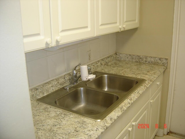 details featuring light countertops, a sink, backsplash, and white cabinetry