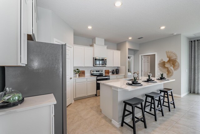 kitchen featuring sink, a kitchen breakfast bar, an island with sink, white cabinets, and appliances with stainless steel finishes