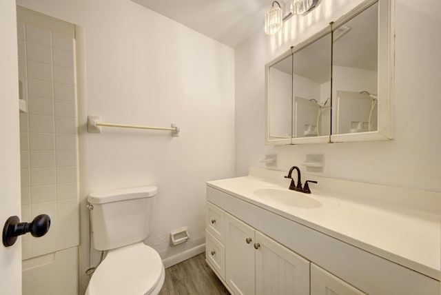 bathroom featuring baseboards, toilet, wood finished floors, walk in shower, and vanity