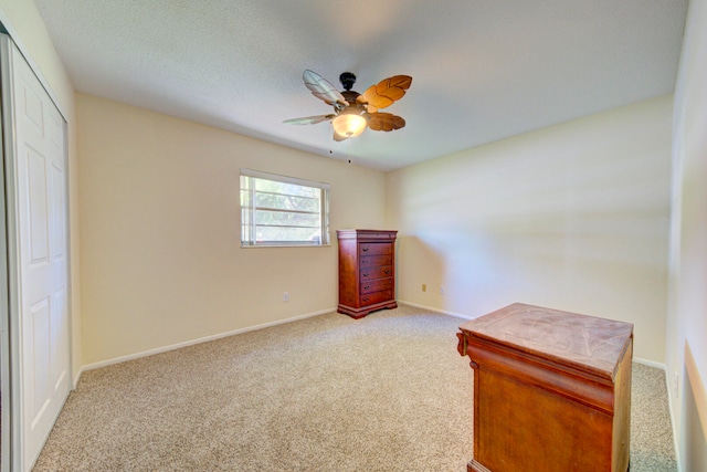 unfurnished bedroom with light carpet, a closet, and ceiling fan