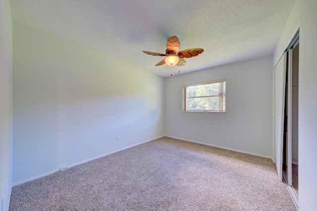 spare room featuring light carpet, ceiling fan, and a textured ceiling