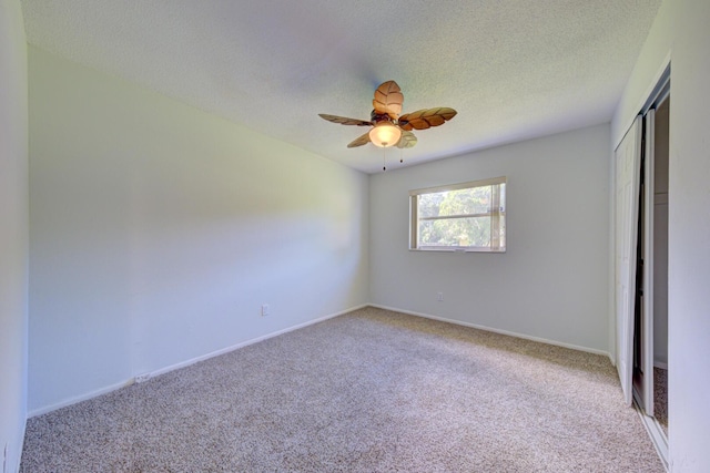 unfurnished bedroom with a textured ceiling, light carpet, a ceiling fan, baseboards, and a closet