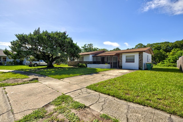 ranch-style home with stone siding, a front lawn, and concrete driveway