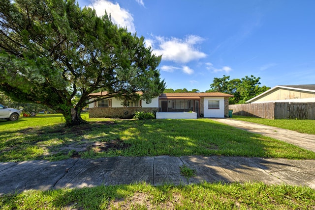 ranch-style house featuring stone siding, a front yard, fence, and stucco siding