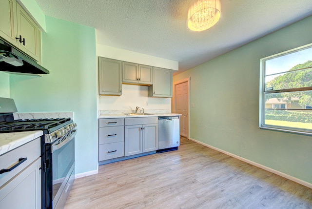 kitchen featuring sink, dishwasher, light hardwood / wood-style flooring, gas range gas stove, and a textured ceiling