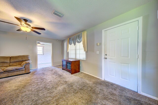 living room with carpet flooring, a textured ceiling, and ceiling fan