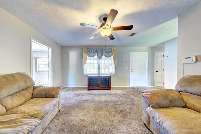 living area featuring plenty of natural light, carpet flooring, visible vents, and a ceiling fan