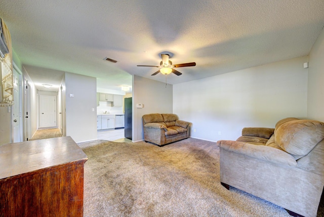 living area with ceiling fan, a textured ceiling, visible vents, and light colored carpet