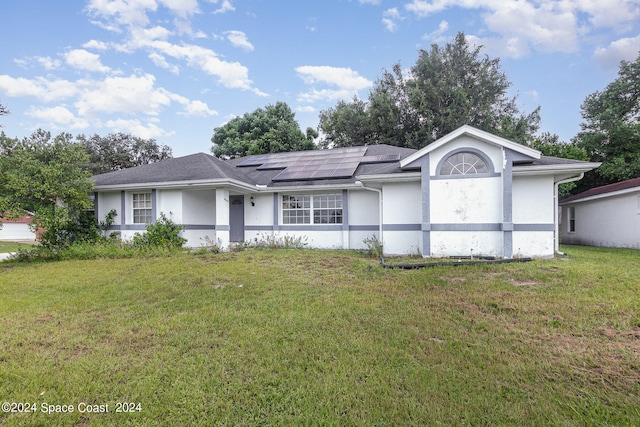 single story home with a front yard and solar panels