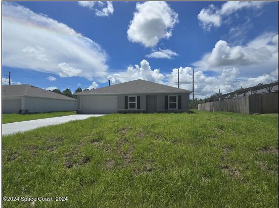 view of front of house featuring a front yard, driveway, an attached garage, and fence