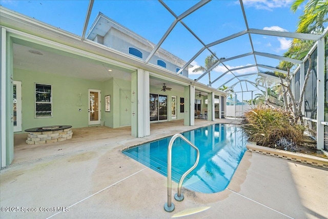 view of pool with a patio, ceiling fan, glass enclosure, and an outdoor fire pit