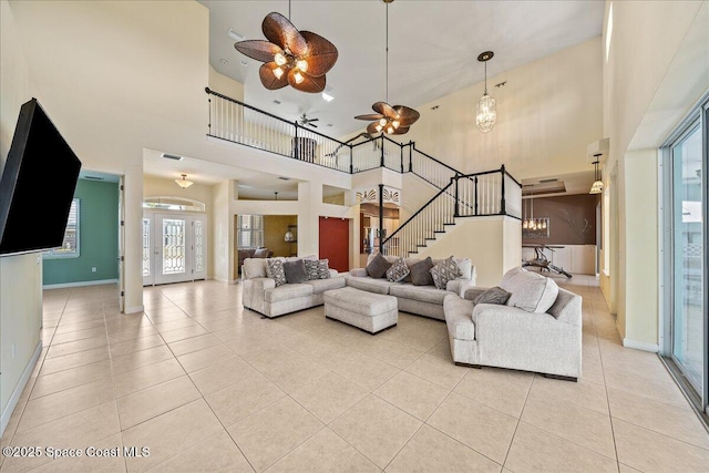 living room featuring ceiling fan with notable chandelier, a high ceiling, and light tile patterned flooring