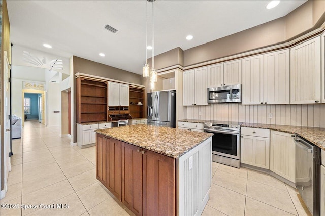 kitchen with light tile patterned flooring, light stone counters, appliances with stainless steel finishes, a kitchen island, and pendant lighting