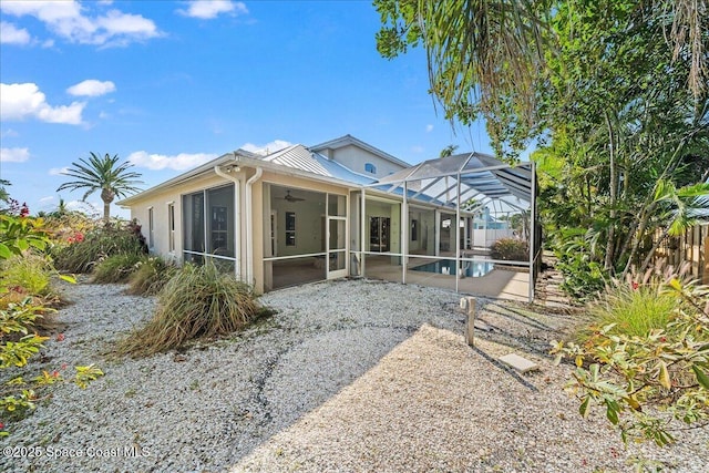 rear view of house featuring a patio area, ceiling fan, and glass enclosure