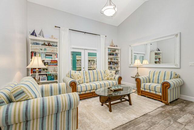 living room with hardwood / wood-style flooring, lofted ceiling, and french doors