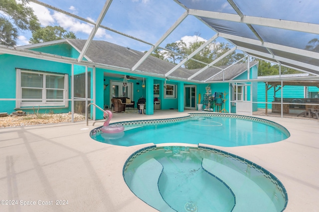 view of swimming pool featuring a patio area, an in ground hot tub, ceiling fan, and glass enclosure