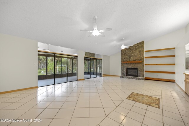 unfurnished living room with ceiling fan, vaulted ceiling, light tile patterned floors, and a fireplace