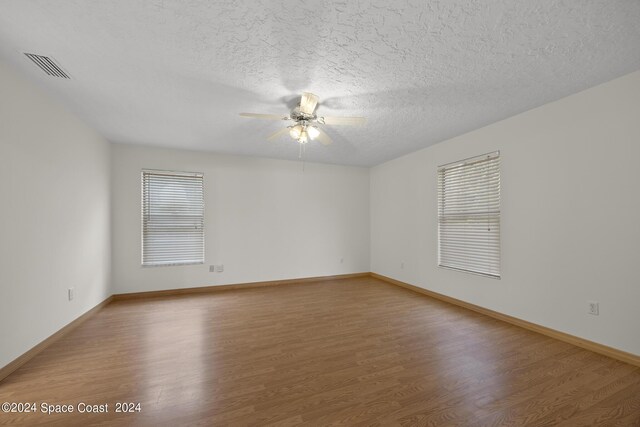 empty room featuring a textured ceiling, ceiling fan, and hardwood / wood-style flooring