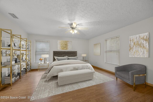 bedroom featuring ceiling fan, wood-type flooring, and a textured ceiling