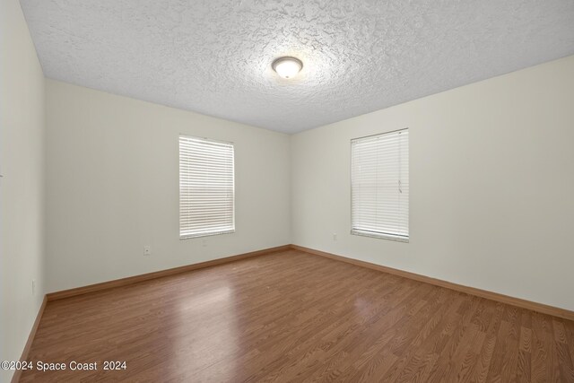 spare room featuring a textured ceiling and wood-type flooring