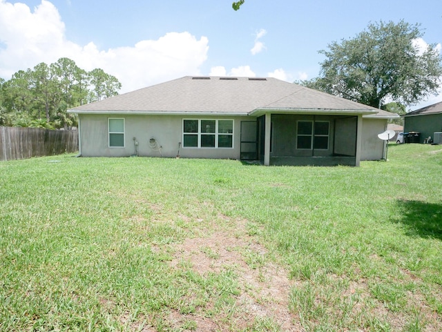 rear view of property with stucco siding, a lawn, and fence