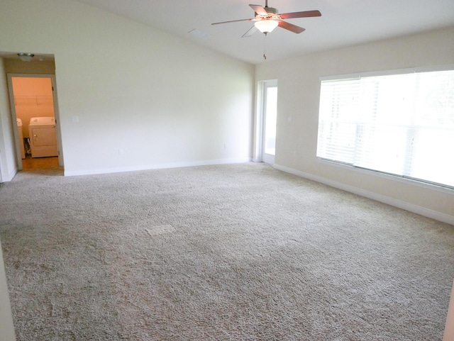 carpeted spare room with ceiling fan, baseboards, vaulted ceiling, and independent washer and dryer