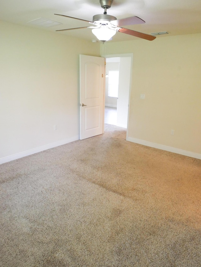 carpeted empty room featuring ceiling fan, visible vents, and baseboards