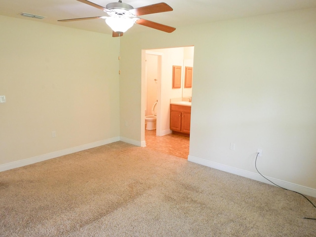 unfurnished bedroom featuring light carpet, baseboards, visible vents, connected bathroom, and ceiling fan