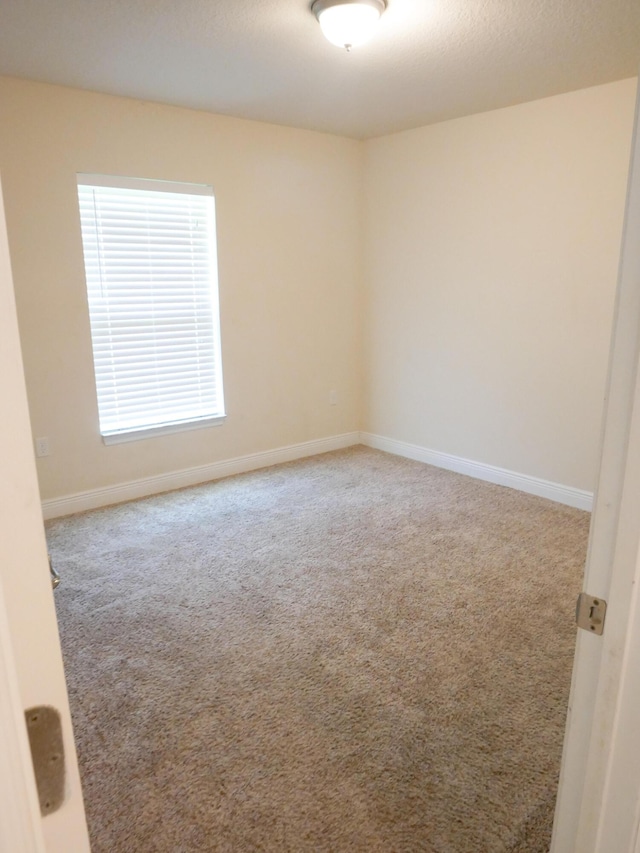 empty room with a textured ceiling, carpet flooring, and baseboards