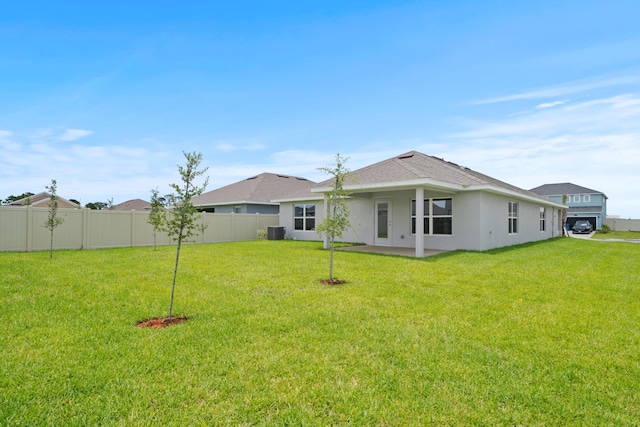 rear view of house with central AC and a lawn