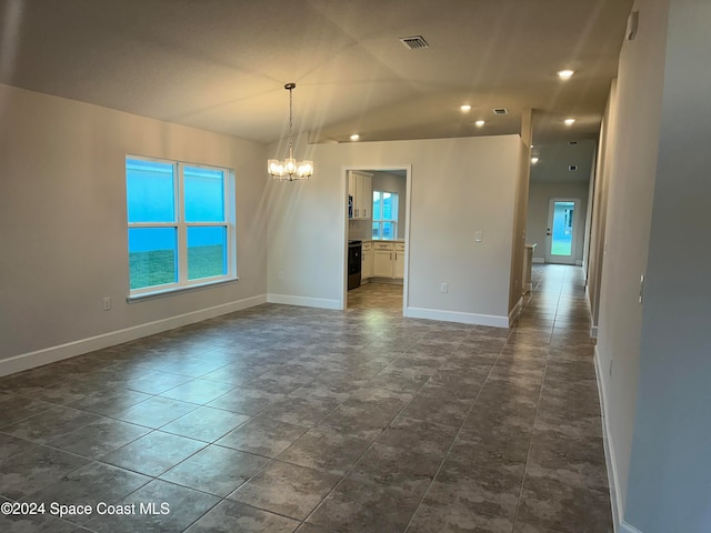 spare room with an inviting chandelier and dark tile patterned flooring