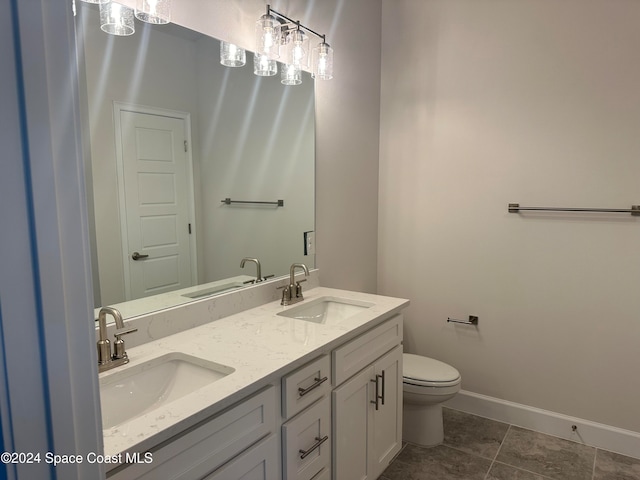 bathroom with toilet, vanity, and tile patterned flooring