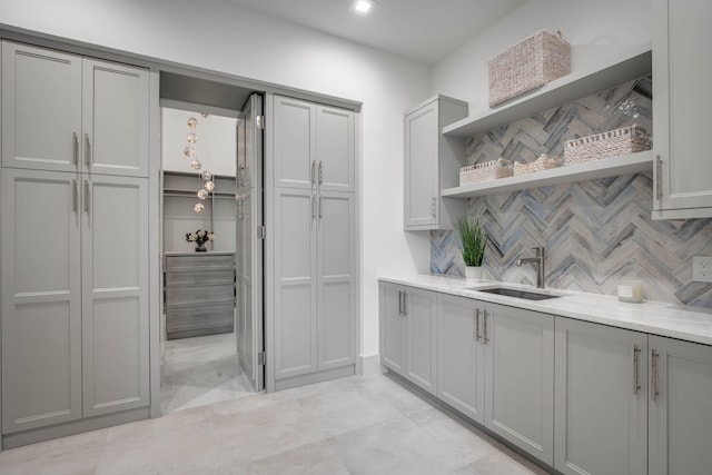 kitchen with gray cabinets, backsplash, light tile patterned flooring, and sink