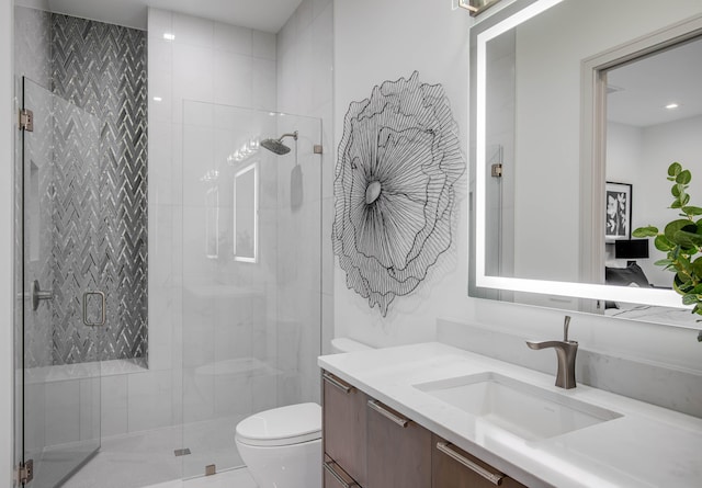 bathroom with a shower with shower door, vanity, and toilet