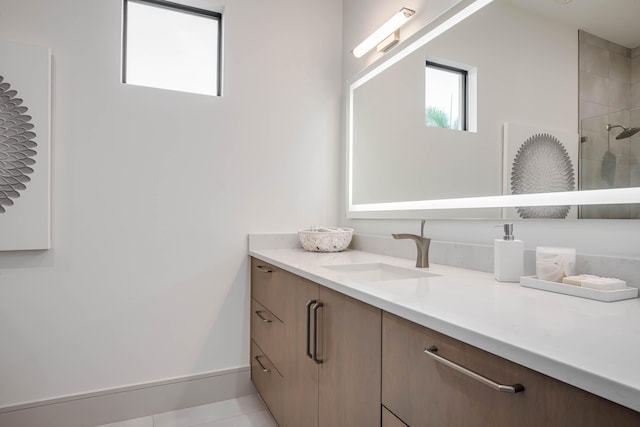 bathroom featuring tile patterned flooring, vanity, and a tile shower