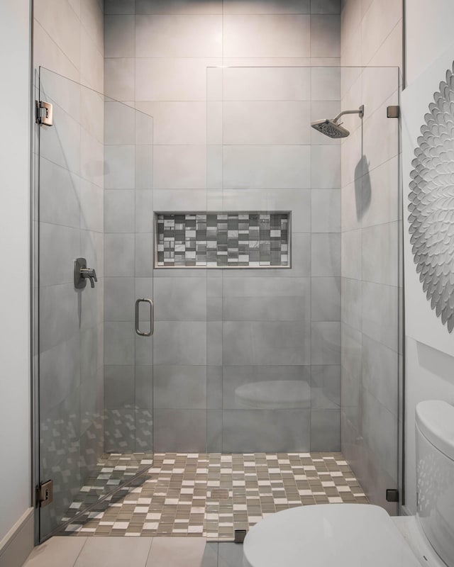 bathroom featuring a shower with door and toilet