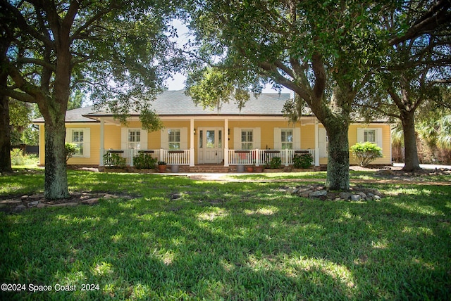 ranch-style house featuring a porch, a shingled roof, and a front lawn