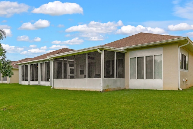 back of house featuring stucco siding, a sunroom, and a yard