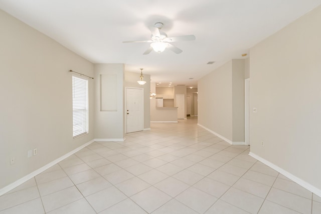 empty room featuring light tile patterned flooring, a ceiling fan, and baseboards