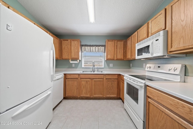 kitchen featuring white appliances, light tile patterned floors, a textured ceiling, and sink